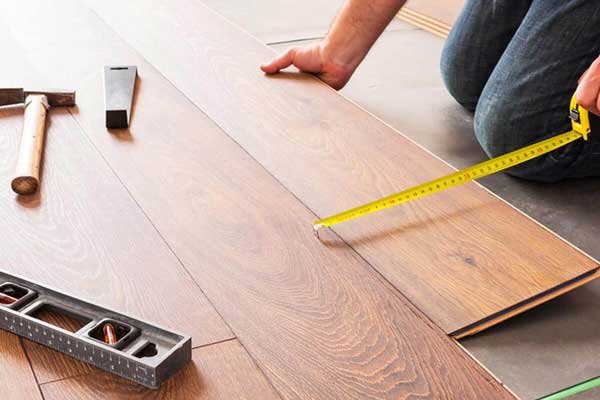 A man is measuring the dimensions of the floor