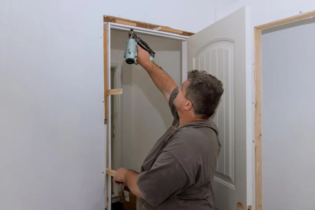 Worker fixing door frame with nail gun