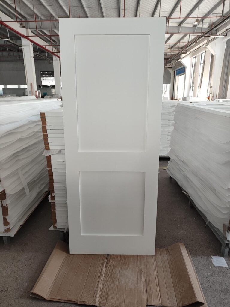 Primed shaker-style interior door stacked in factory warehouse