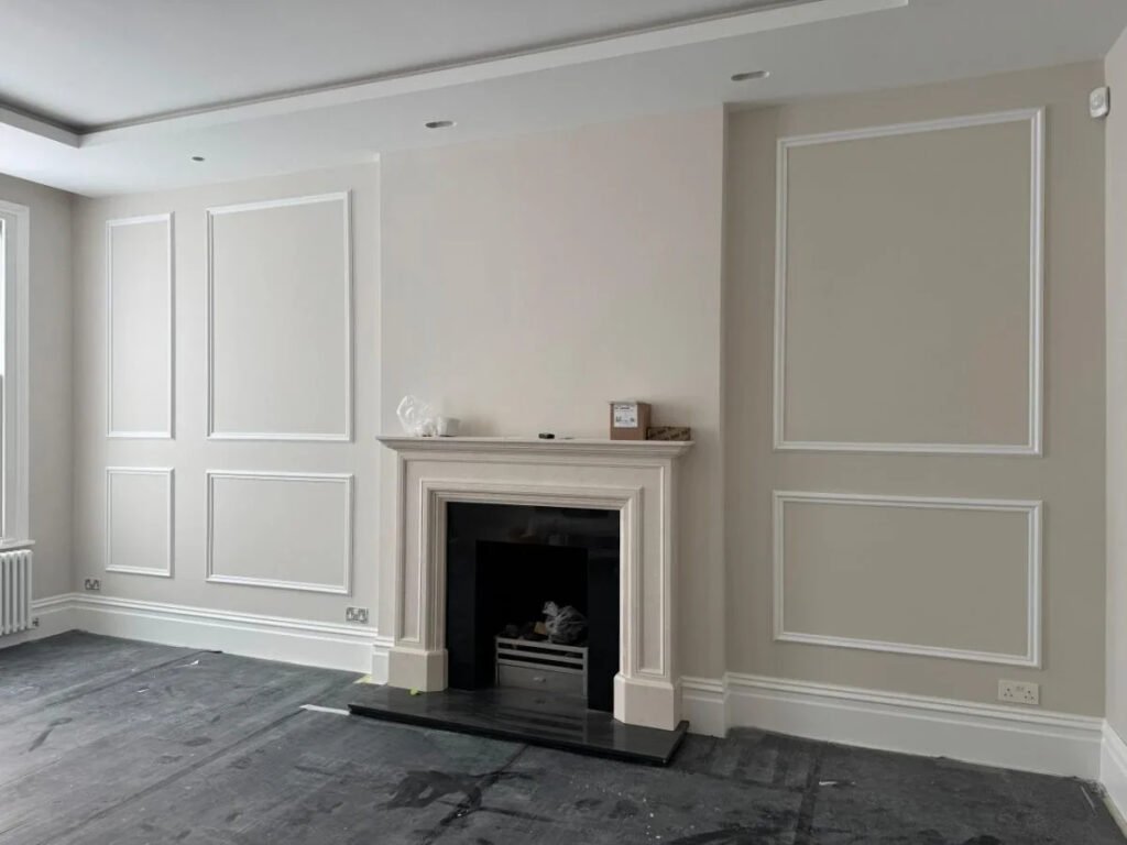 Elegant living room with decorative wall panel moulding and a traditional fireplace.