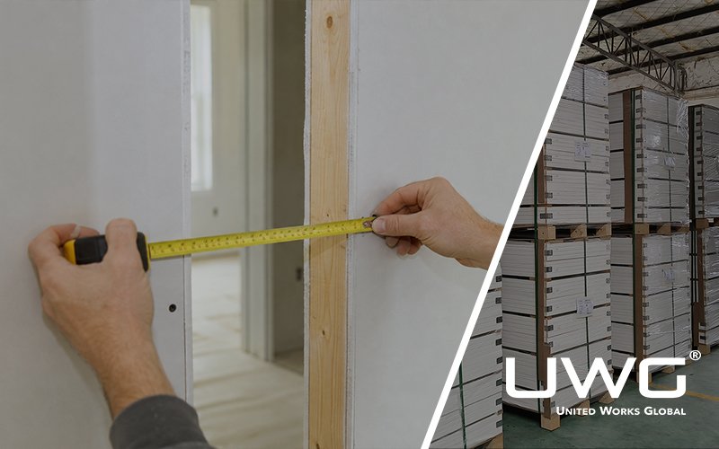 Contractor measuring finished wall thickness across a 2×4 drywall partition