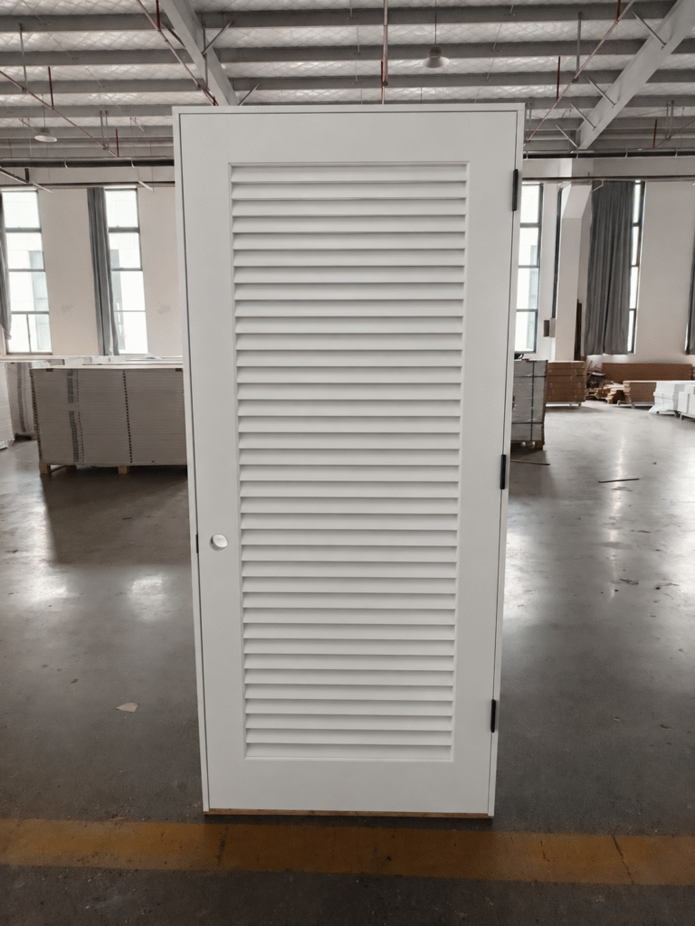White full-louvered door with two vented panels in a factory setting